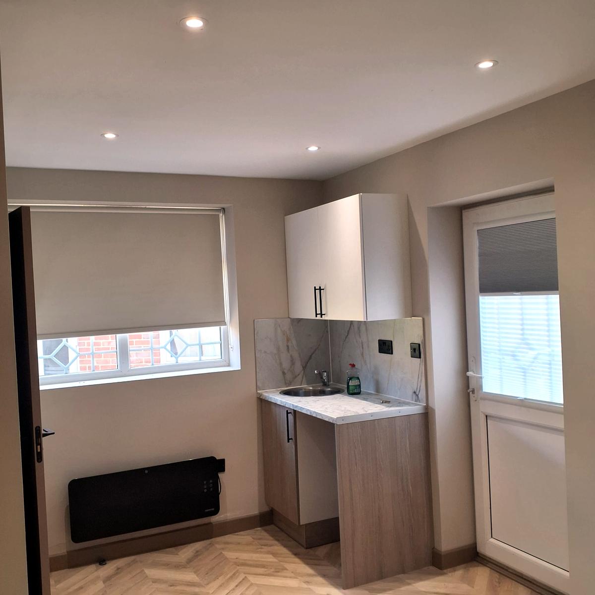 Studio kitchenette with a roller blind on the window and a blind on the door